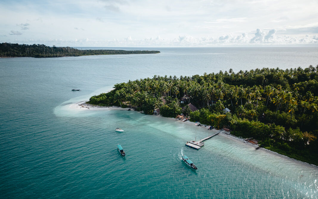 Stunning overhead drone photo of the Shadow Mentawai Surf Camp in the Mentawai Islands showing the resort with 3 of their amazing speed boats that can take surfers to the waves. 